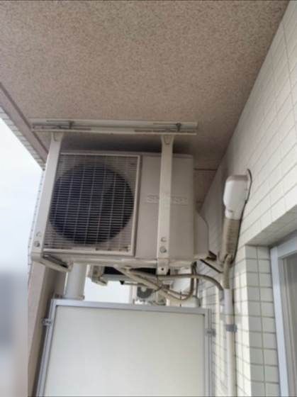 交換前にバルコニーの吊り金具へ設置されていたシャープ製室外機（施工前）