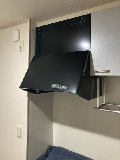 交換前のキッチンに設置されていた古い黒色のレンジフード（施工前）