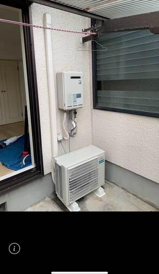 戸建住宅の勝手口に給湯器を避けて地面置き設置した富士通製エアコン室外機（施工後）